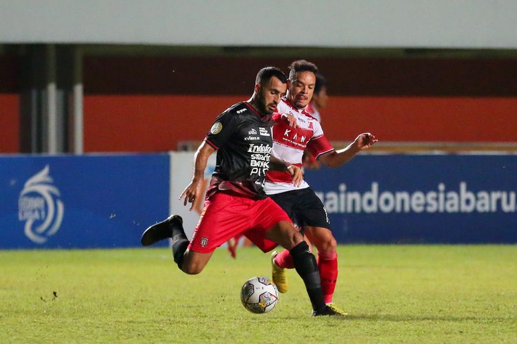Pemain Bali United Brwn Nouri dijaga ketat pemain Madura United Lulinha saat pertandingan pekan ke-14 Liga 1 2022-2023 yang berakhir dengan skor 1-3 di Sadion Maguwoharjo Sleman, Senin (12/12/2022) malam.