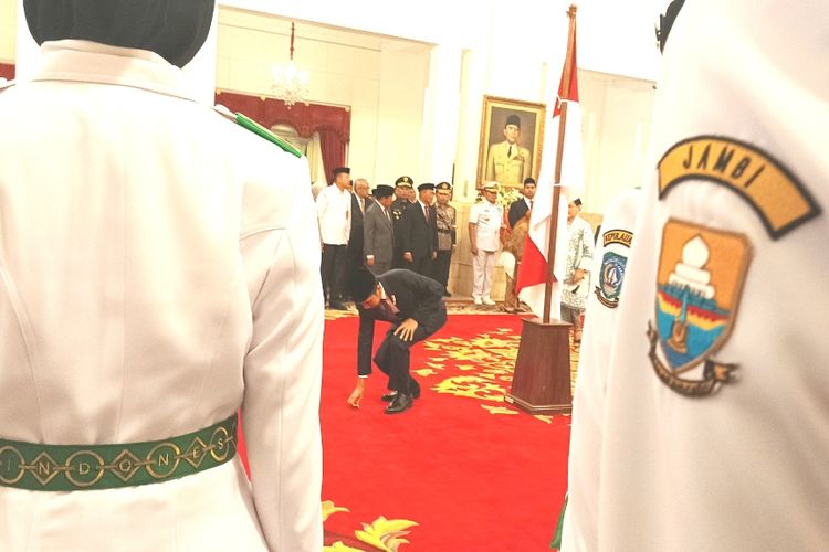 Presiden Joko Widodo saat berjongkok mengambilkan pin pengukuhan paskibraka yang terjatuh di Istana Negara, Jakarta, Selasa (15/8/2023).