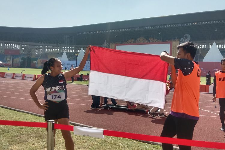 Ni Made Arianti (kiri) membentangkan bendera Merah Putih bersama sang pendamping, Bayu, usai meraih medali emas nomor lari 100 meter T12 putri di Stadion Manahan, Solo, Senin (1/8/2022) siang WIB.