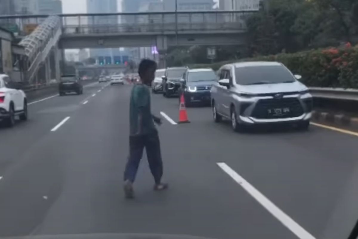 Seorang pria berjalan di tengah jalan tol dalam kota Semanggi mengarah Kuningan, Jakarta pada Rabu (13/7/2022) pagi.