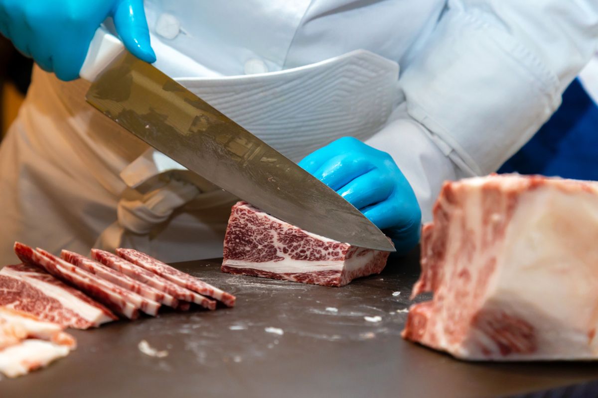Ilustrasi tukang daging memotong wagyu grade A5, daging sapi mahal khas Jepang berkualitas tinggi. 