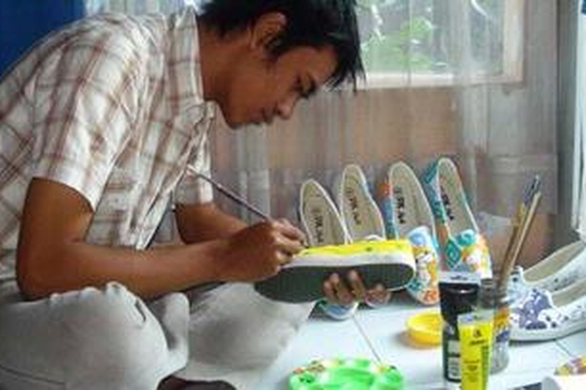 Angling Aditya Purbaya (20), tengah menyelesaikan sebuah pesanan sepatu lukis bergaya Manga yang akan dikirim ke Taiwan, Kamis (17/3/2011).
