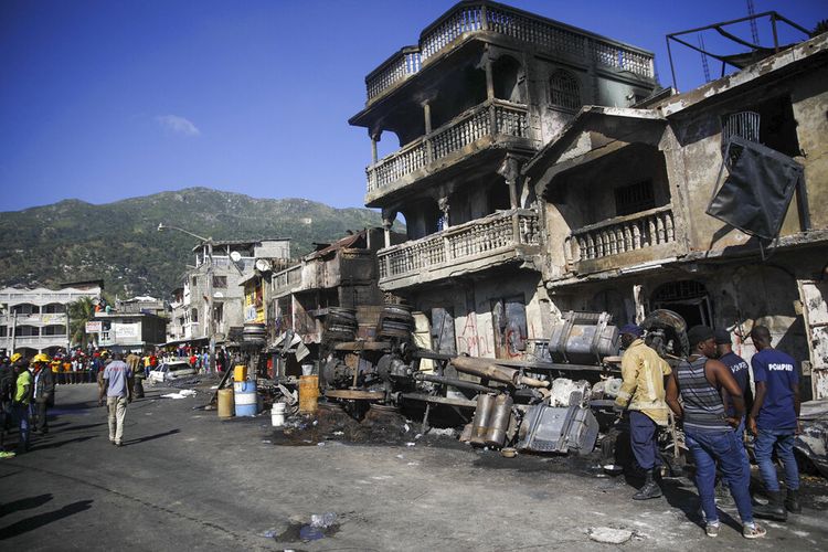 Petugas pemadam kebakaran berdiri di samping sisa-sisa truk yang membawa bensin setelah terbalik dan meledak di Cap-Hatien, Haiti, Selasa, 14 Desember 2021. 