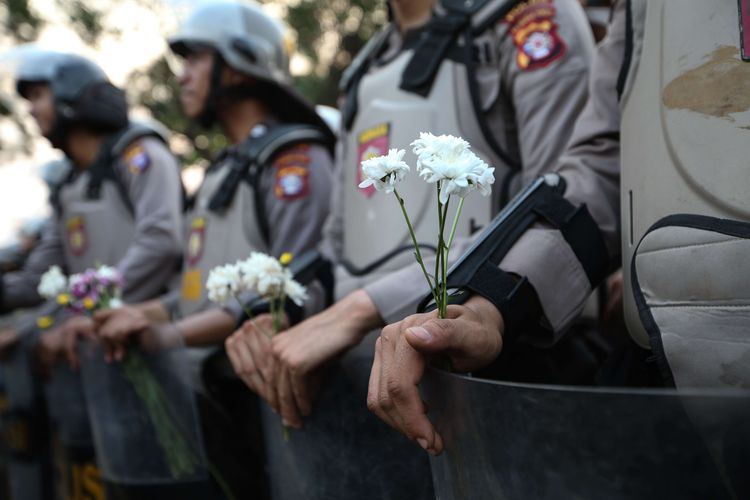 Polisi menerima bunga saat aksi damai mahasiswa di bawah jembatan layang Senayan, Jakarta, Selasa (1/10/2019). Mahasiswa menolak Rancangan Kitab Undang-Undang Hukum Pidana (RKUHP) dan Undang-Undang Komisi Pemberantasan Korupsi (UU KPK).