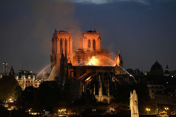 Api membakar bagian atas Gereja Notre Dame di Paris, Perancis, pada Senin (15/4/2019). Belum diketahui penyebab pasti kebakaran itu, api dengan cepat melalap atap dan puncak menara gereja bernuansa Gotik yang dibangun pada abad ke-12 itu.