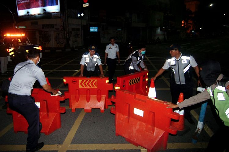 Petugas melakukan pengalihan jalur saat penutupan sebagian jalan protokol Kota Tegal, Jawa Tengah, Senin (22/3/2020) malam. Pemerintah Kota Tegal dan Polres Tegal hingga 14 hari mendatang melakukan lockdown lokal dengan menutup jalur Pantura yang melintasi Kota Tegal, akses masuk Alun-alun Tegal dan mematikan sebagian lampu jalan protokol guna pembatasan kendaraan yang akan masuk ke Kota Tegal dan mencegah adanya kerumunan massa di jalan untuk mencegah penyebaran COVID-19. ANTARA FOTO/Oky Lukmansyah/aww.