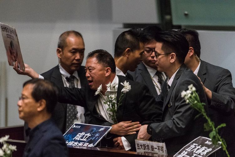 Politisi pro-demokrasi Wu Chi-wai (tengah dengan tangan memegang kertas) meneriakkan slogan kepada Kepala Eksekutif Hong Kong Carrie Lam ketika memberikan keterangan dalam sidang Kamis, 17 Oktober 2019. Lam terpaksa membatalkan pidato kenegaraan pada Rabu (16/10/2019) setelah menerima ejekan dari para politisi pro-demokrasi.