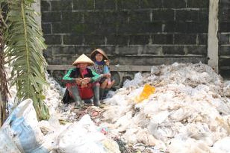 Pemungut sampah ditemani lalat beristirahat sembari menyantap makanan. 