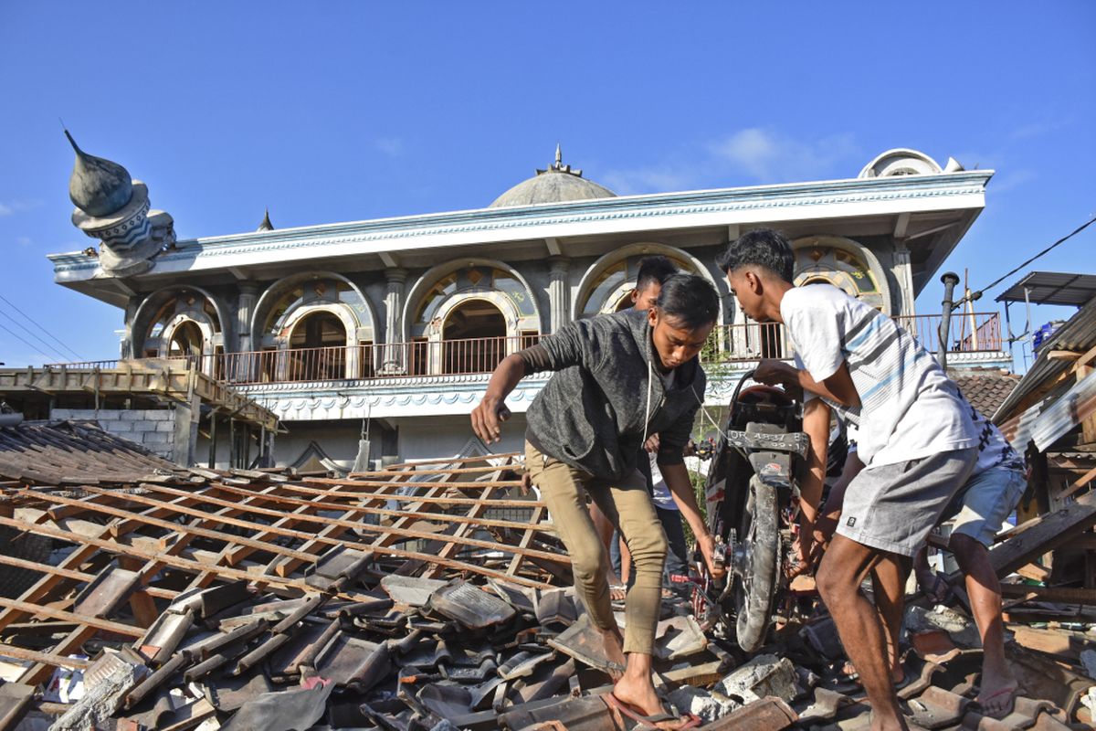 Warga mengangkat sepeda motornya dari reruntuhan rumah pascagempa di Desa Wadon, Kecamatan Gunungsari, Lombok Barat, NTB, Senin (6/8/2018). Gempa bumi bermagnitudo 7 mengguncang Lombok, Minggu (5/8/2018) malam.