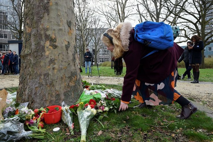 Seorang perempuan meletakkan bukan di lokasi penembakan trem di Lapangan 24 Oktober Utrecht, Belanda. 