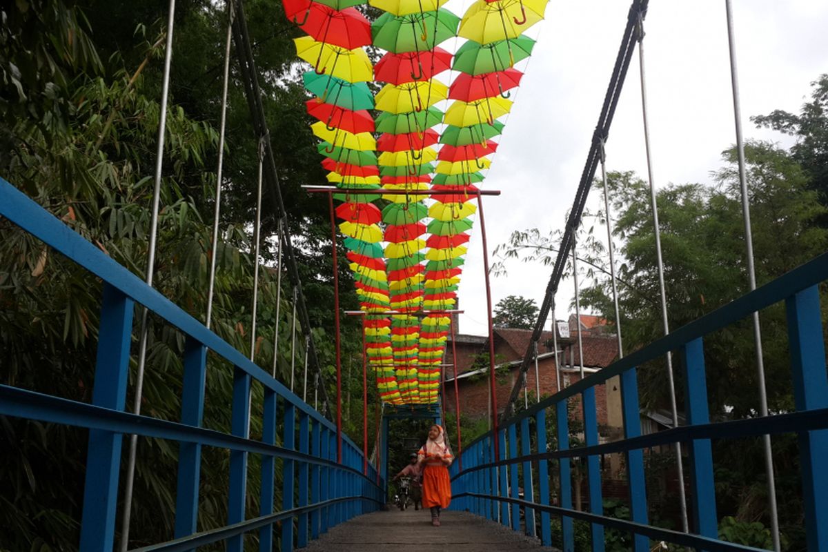Sejumlah siswa SD saat melintas di atas jembatan gantung di RT 6 RW 5 Kelurahan Penanggungan, Kecamatan Klojen, Kota Malang, Jawa Timur, Selasa (14/11/2017). Jembatan itu dihias dengan payung supaya kelihatan lebih indah.