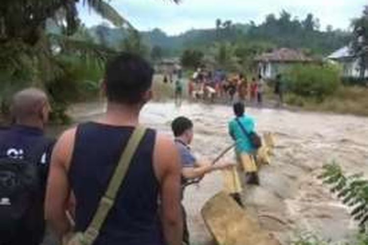 Hujan deras sejak dua hari terakhir menyebakan jembatan desa yang menghubungkan desa-desa lain di sekitarnya terputus dihantam banjir bah, sejak sabtu kemarin. Sejumlah warga nekad menyeberangi sungai dengan menggunakan tali yang ditambatkan di kedua siis sungai.