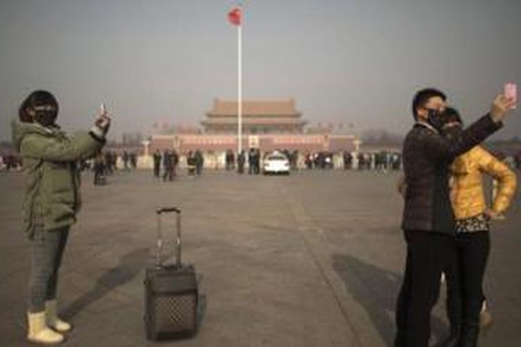 Asap tebal yang menyelimuti kota Beijing, China membuat para turis yang mengunjungi Lapangan Tiananmen ini harus rela berfoto sambil mengenakan 