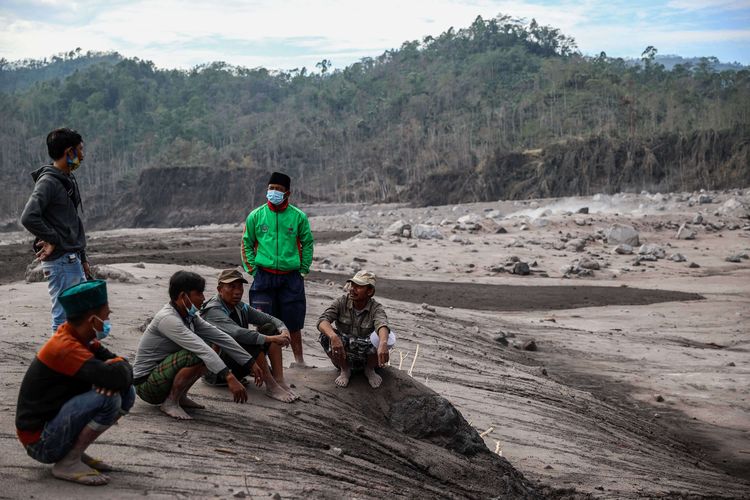 Warga menunggu kerabat mereka yang tertimbun saat operasi pencarian korban yang tertimbun material guguran awan panas Gunung Semeru di Desa Curah Kobokan, Kecamatan Candipuro, Lumajang, Jawa Timur, Selasa (7/12/2021). Berdasarkan data Badan Nasional Penanggulangan Bencana (BNPB) per Senin (06/12) pukul 20.15 WIB, setidaknya 22 orang tewas, sementara 22 orang dinyatakan hilang dan 56 lainnya mengalami luka-luka. Erupsi juga berdampak terhadap 5.205 jiwa.