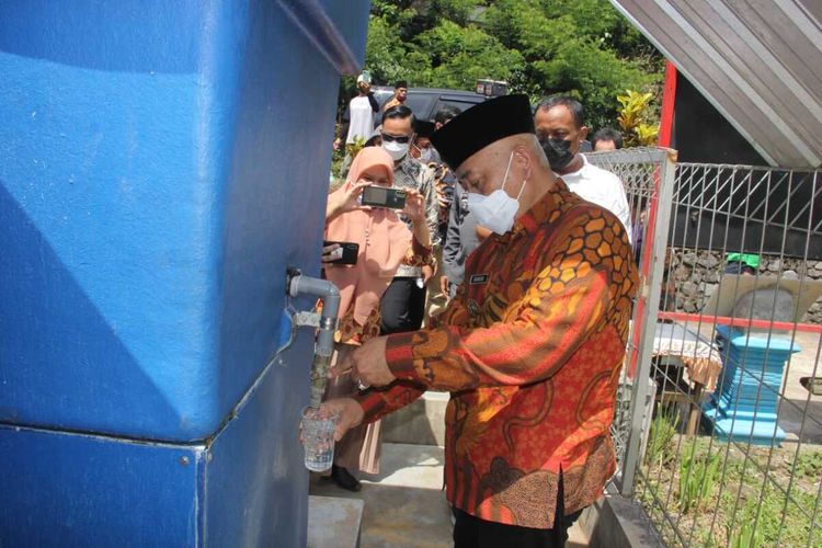 Bupati Malang, HM Sanusi saat mencoba air minum hasil olahan unit penjernih air.