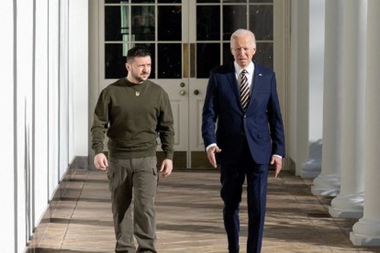 Presiden AS Joe Biden berjalan dengan Presiden Ukraina Volodymyr Zelensky melalui barisan tiang Gedung Putih, di Washington, DC pada 21 Desember 2022.
