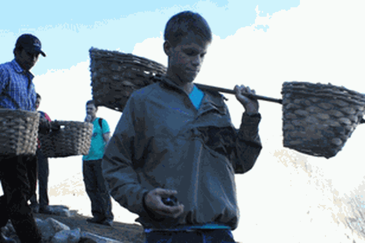 Seorang wisatawan asing membawa keranjang belerang di Kawah Ijen.