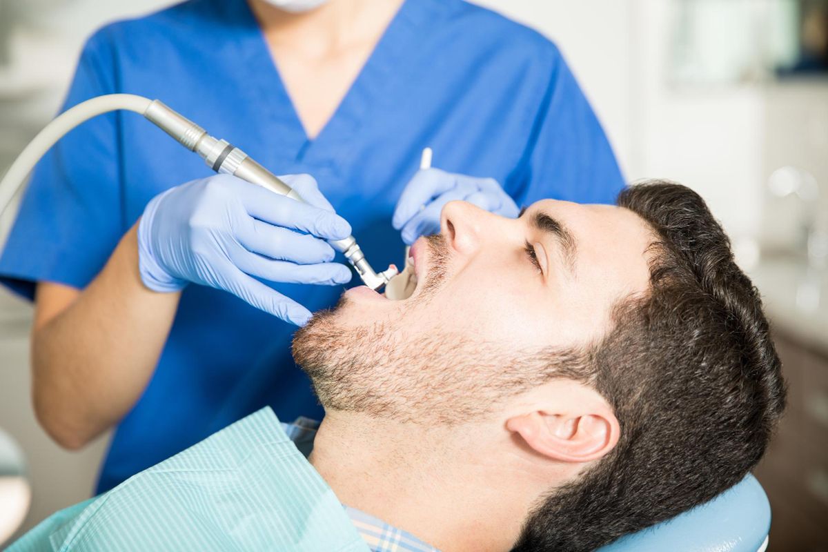 Dokter gigi sedang melakukan prosedur polishing gigi pada pasien