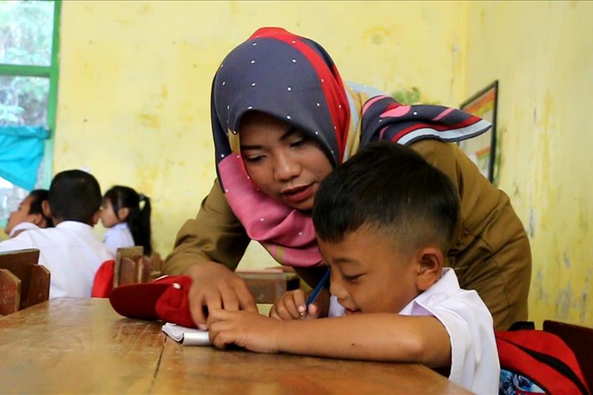 Atun Rohayatun (24) menemani dan mengajarkan Jodi (7) di ruang kelas 1, SDN Margabakti, Kecamatan Kadugede, Kabupaten Kuningan, Jawa Barat, Senin (29/7/2019)