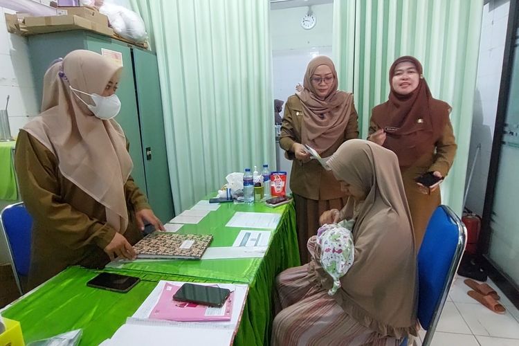 Siti Maimunah menggendong anaknya dengan ditemani bidan dan kepala Puskesmas Pamolokan