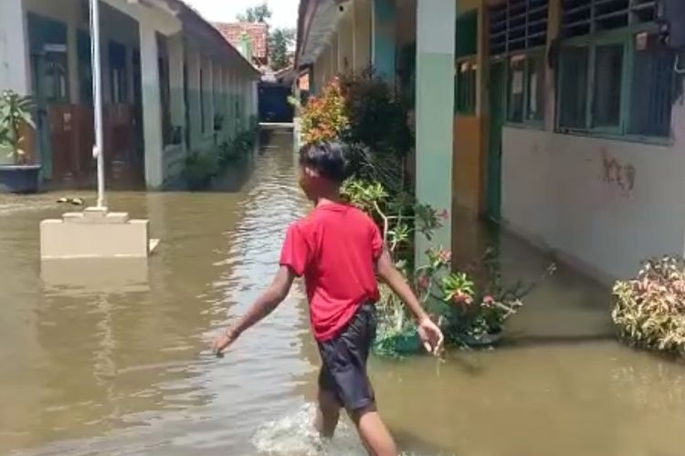Siswa berjalan di tengah genangan sekolahnya di Kabupaten Brebes, Jawa Tengah yang terendam banjir akibat luapan Sungai Pemali, Senin (21/11/2022) (Istimewa)