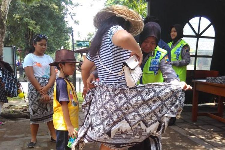 Wisatawan yang memakai celana atau rok pendek wajib mengenakan sarung saat ke Candi Borobudur, Minggu (27/3/2016).