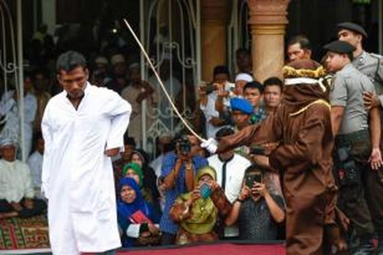Eksekutor melakukan pencambukan terhadap terpidana maisir atau judi di halaman Masjid Besar Pahlawan, Peuniti, Banda Aceh, Jumat (19/9/2014).