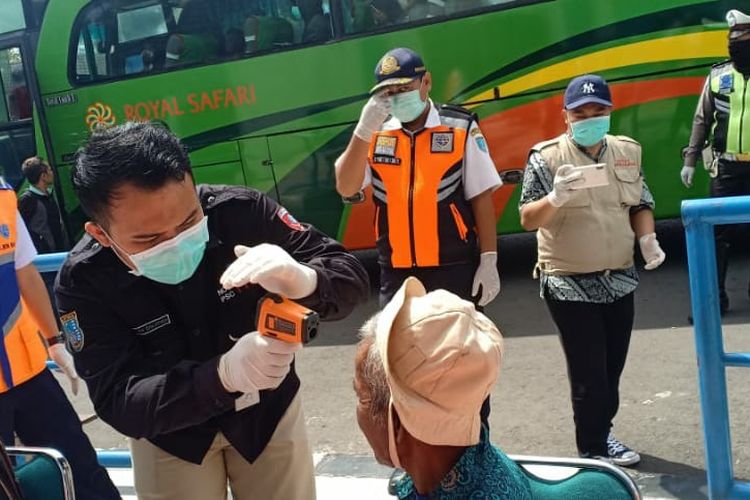 Petugas memeriksa suhu tubuh penumpang bus yang turun d Kota Salatiga.