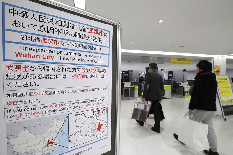 Penumpang berjalan melalui papan pemberitahuan terkait penyebaran virus Corona di Bandara Narita, 16 Januari 2020.