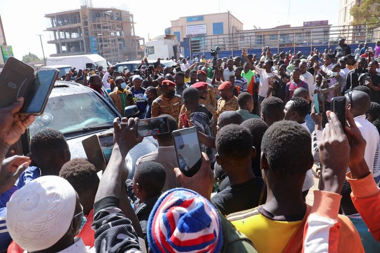 Orang-orang berkumpul di sekitar kendaraan milik kepresidenan setelah Presiden Burkina Faso Roch Kabore ditahan di sebuah kamp militer menyusul baku tembak di dekat kediaman presiden di Ouagadougou, Burkina Faso, 24 Januari 2022. 