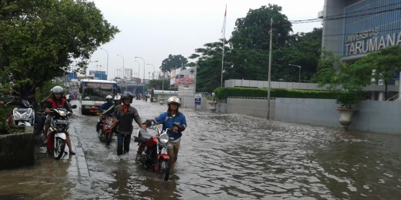 Sejumlah warga yang sepeda motornya mengalami mogok saat melewati banjir di Jalan S Parman, tepat di depan Universitas Tarumanagara, Jakarta Barat, Rabu (5/2/2014)