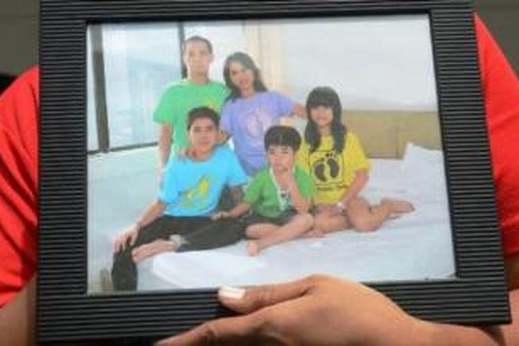 Kerabat membawa foto keluarga Hermanto Tanus di Crisis Center Bandara Juanda, Senin (29/12/2014). Tampak di foto Chiara (kaos kuning) bersama saudara dan kedua orangtuanya. 