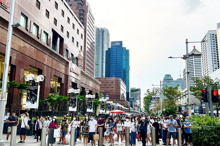Warga Singapura menunggu untuk menyeberang di surga belanja Orchard Road, Minggu (10/7/2022) sore. Mayoritas warga Singapura memilih tidak menggunakan masker lagi ketika berada di ruang terbuka atau outdoor menyusul relaksasi besar-besaran Covid-19 untuk menormalisasi kehidupan sehari-hari di Singapura.