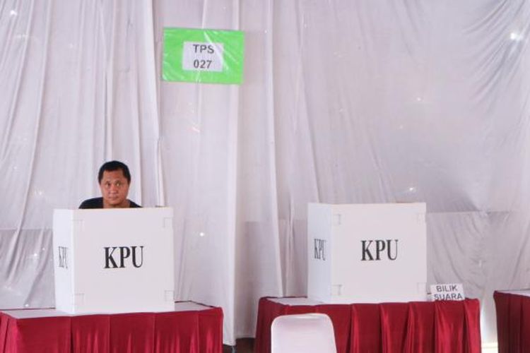 Salah satu wartawan radio nasional tetap mencoblos di sela pekerjaannya meliput proses pemungutan suara, di TPS 027 Kebagusan, Jakarta Selatan Rabu (15/2/2017).