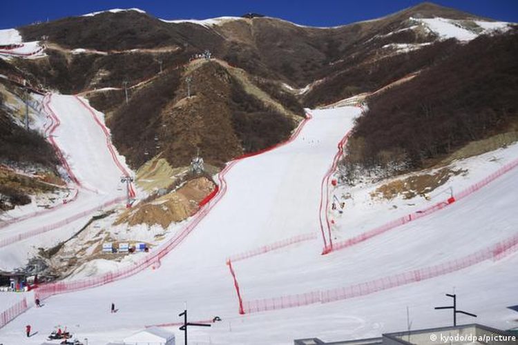 Sisi gunung yang kosong kontras dengan jalur salju yang dibuat sepenuhnya oleh mesin untuk acara ski Olimpiade Beijing.