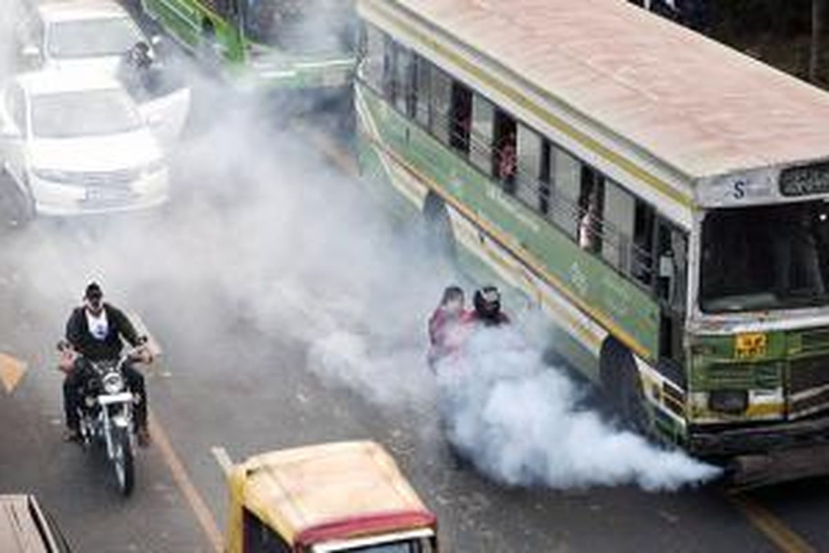 Bus publik menanti lampu hijau di persimpangan jalan. 