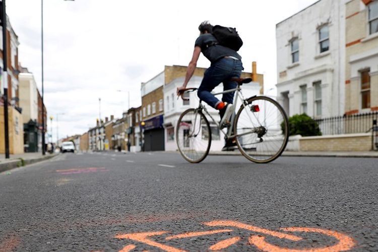 A cyclist cycles by painted stencils on a street to create pop up bike lanes in preparation for distanced bike rides, following the outbreak of the coronavirus disease (COVID-19), London, Britain, May 16, 2020. REUTERS/Peter Nicholls