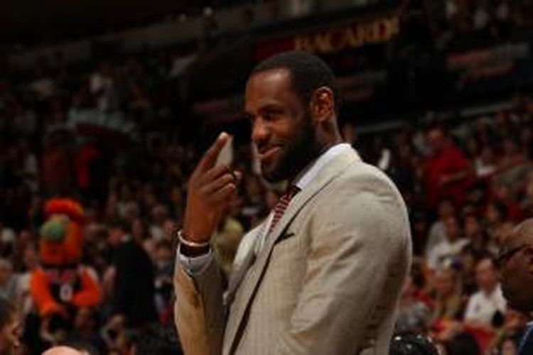 Pebasket Miami Heat LeBron James tersenyum dari sisi lapangan saat timnya bertemu Chicago Bulls di American Airlines Arena pada 3 Ferbuari 2014.