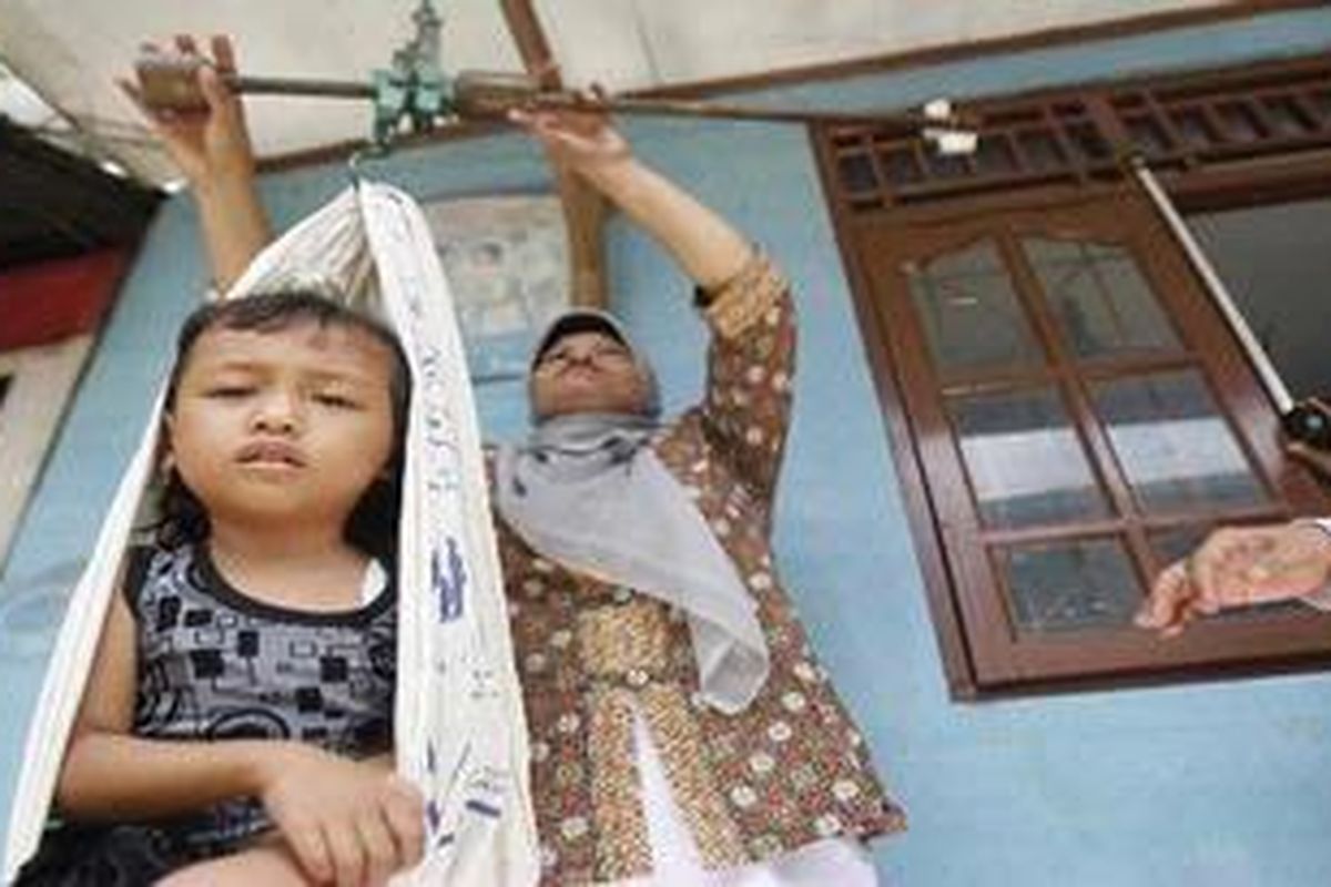 Seorang anak ditimbang berat badannya di sebuah posyandu.