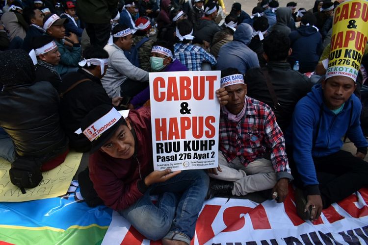 Salah satu demonstran dari Serikat Tukang Gigi Indonesia (STGI) tengah memperlihatkan poster berisi tuntutan dicabutnya pasal 276 ayat 2 RKUHP, karena dinilai mematikan mata pencaharian tukang gigi.