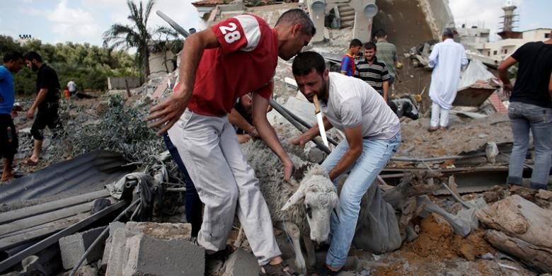 Seorang warga Gaza menyelamatkan seekor kambing dari sebuah bangunan yang hancur akibat serangan udara Israel sepanjang Selasa (15/7/2014). Israel kembali melakukan serangkaian serangan ke Jalur Gaza setelah Hamas menolak usulan gencatan senjata yang diajukan Mesir.