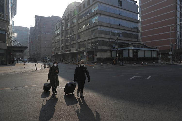 Dua orang mengenakan masker berjalan di jalanan kosong di tengah pembatalan perayaan Tahun Baru Imlek di Beijing, China, di tengah merebaknya virus corona pada 25 Januari 2020.