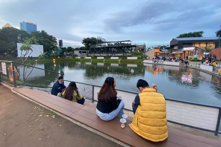 Pengunjung yang duduk-duduk di pinggir danau buatan di kawasan CIBIS Park, Jakarta Selatan. 
