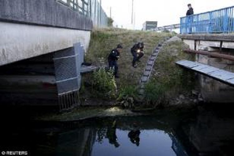 Petugas polisi Perancis mencari para migran di bawah jembatan di Calais, di dekat sebuah pagar Eurotunnel