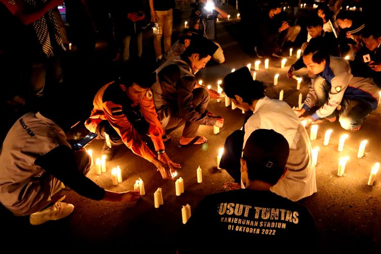 Seorang peserta menggunakan kaos bertulis usut tuntas sebelum doa bersama Aremania bahu membahu menyalakan lilin untuk memperingati 100 hari Tragedi Kanjuruhan di halaman Stadion Kanjuruhan Kepanjen, Kabupaten Malang, Senin (9/1/2023) malam.