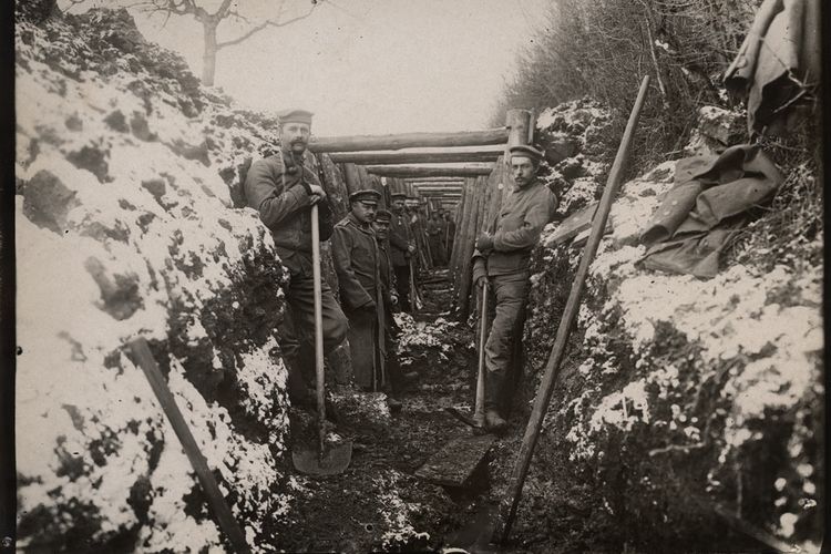 Tentara Jerman di parit, bersandar di dinding dengan sekop dan beliung