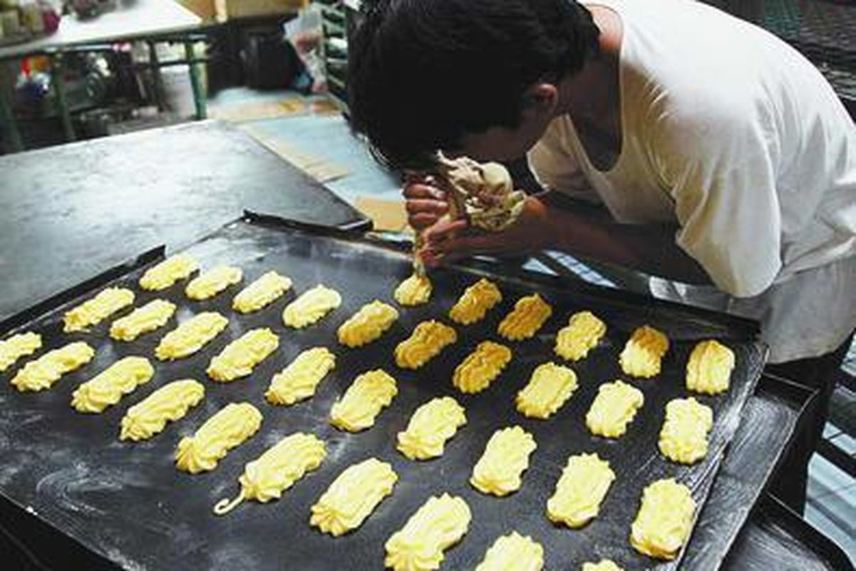 Pekerja di toko roti Maison Benny, Cikini, Jakarta Pusat, menyelesaikan pembuatan kue soes, Jumat (12/9).  