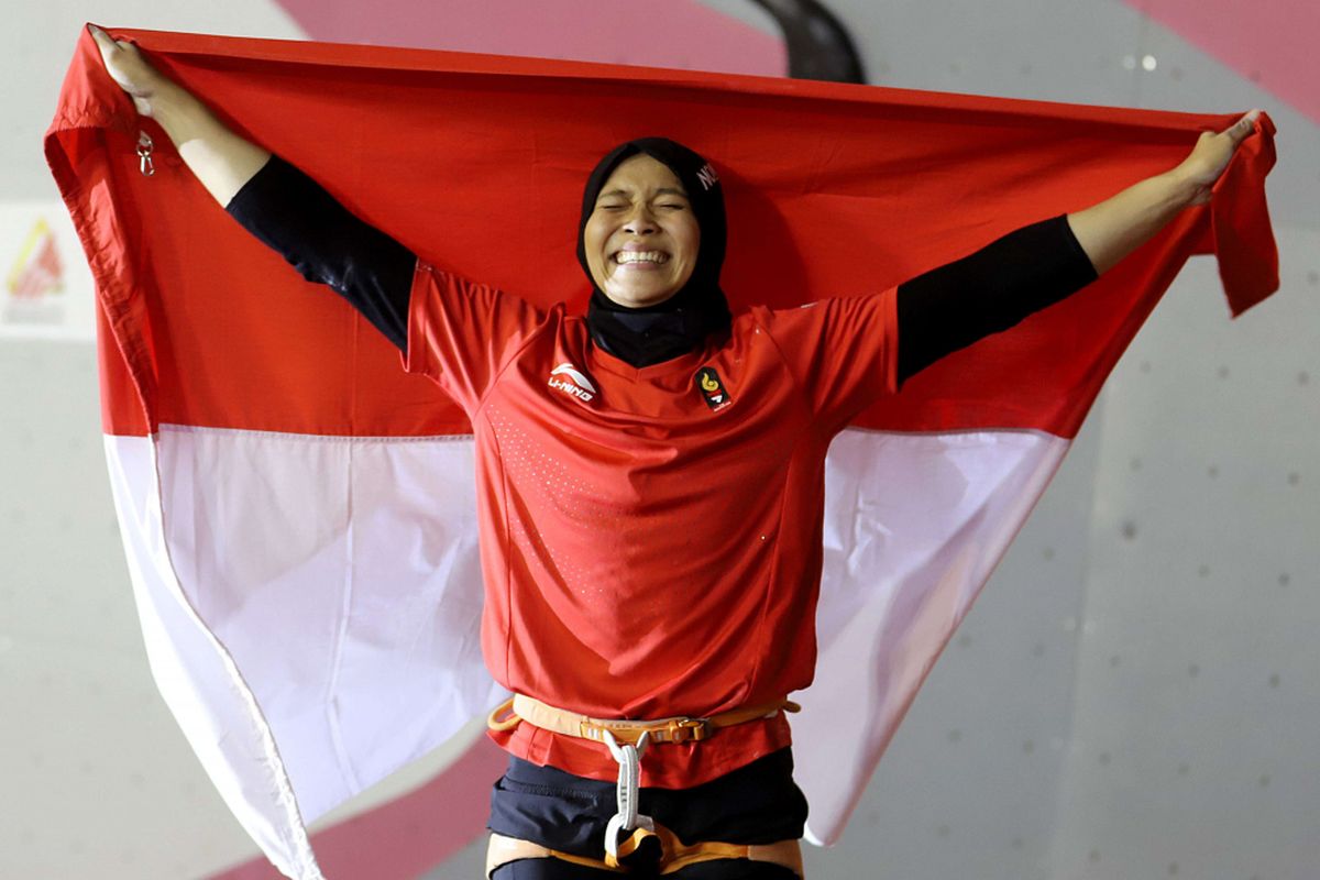 Atlet panjat tebing Indonesia Aries Susanti Rahayu mengibarkan Bendera Merah Putih setelah berhasil meraih medali emas pada kategori speed Asian Games 2018 di Arena Panjat Tebing Jakabaring Sport City, Palembang, Sumatera Selatan, Kamis (23/8/2018).