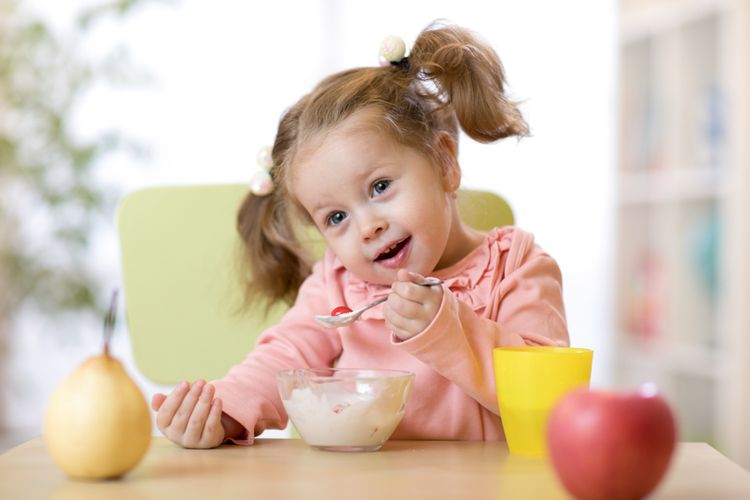 Ilustrasi anak belajar makan sendiri, makan sendiri tanpa banyak sisa makanan tumpah adalah salah satu tahapan tumbuh kembang anak usia 2 tahun. 