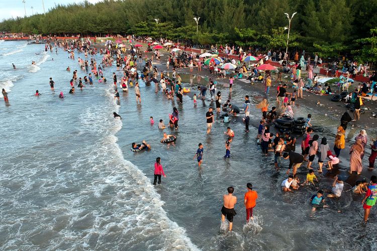 Foto udara wisatawan bermain air di Pantai Alam Indah (PAI) Tegal, Jawa Tengah, Selasa (3/5/2022). Pantai yang terletak di pinggir jalur Pantura itu menjadi salah satu tujuan wisata dari dalam maupun luar Kota Tegal saat libur lebaran.